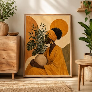 May include: A framed art print depicting a woman in a yellow head wrap and dress, holding a vase of green plants. The artwork uses a warm colour palette with orange and brown tones. The background features abstract shapes.