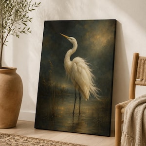 May include: A rectangular canvas wall art print featuring a white egret standing in shallow water. The bird has long, flowing white feathers and a yellow beak. The background is a dark, moody landscape with golden light reflecting on the water.