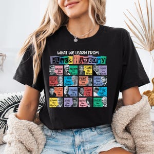 May include: Black t-shirt with the text "WHAT WE LEARN FROM BLACK HISTORY" and portraits of historical figures. The shirt features a grid of images with phrases like "Challenge like Rosa" and "Inspire like Louis."