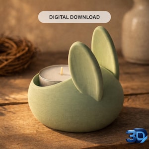 Op de afbeelding: Een lichtgroene kandelaar in de vorm van een konijn met een brandende waxinelichtkaars erin. De oren van het konijn staan rechtop. De woorden "DIGITALE DOWNLOAD" staan in een lichtbeige rechthoek boven de kandelaar. De kandelaar staat op een houten oppervlak.