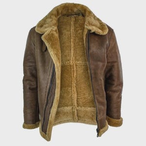 Puede incluir: Chaqueta de cuero marrón con forro y cuello de borrego. La chaqueta tiene cierre de cremallera y un estilo aviador clásico. El interior es de color beige cálido y el cuero exterior tiene un aspecto envejecido.