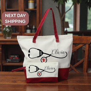A red and white tote bag with a stethoscope design and the name "Olivia" printed on it, along with a smaller white bag with the same design and name. The bag is placed on a wooden surface, and there is a "Next Day Shipping" sign in the background.