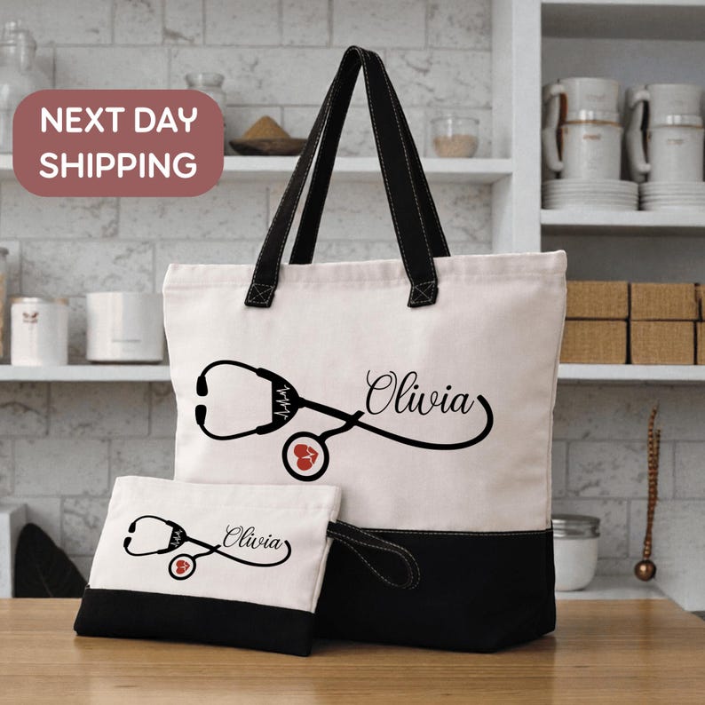 A tote bag with a stethoscope design and the name "Olivia" printed on it, along with a smaller bag with the same design and name. The bag is placed on a wooden surface, and there are shelves and kitchen items in the background.