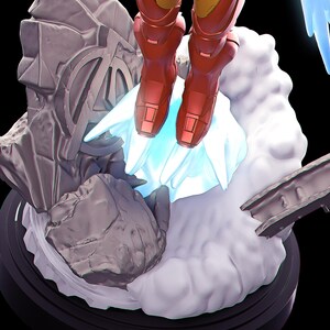 May include: A detailed figurine of a superhero in a red and gold suit, hovering above a cloud-like base. The base features a rock formation and the Avengers logo. The figure is on a black circular base with blue light effects.