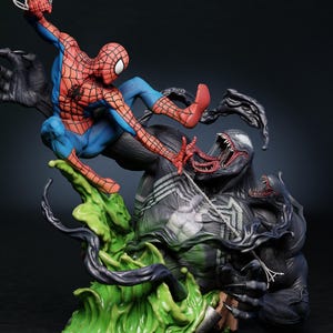 May include: A detailed figurine depicting Spider-Man in a dynamic pose, battling Venom. Spider-Man is in his classic red and blue suit, while Venom is a menacing black figure with a large mouth. The base features green and black elements.