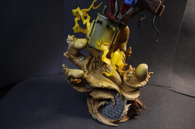 May include: A detailed figurine featuring a stylized, weathered base with a textured, tree-like appearance. The figurine has a green and yellow container, with yellow lightning bolt accents. The figure is set against a dark background.