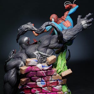 May include: A detailed figurine depicting Spider-Man battling Venom. Spider-Man is in a dynamic pose, clad in his classic red and blue suit. Venom is a large, dark figure with a menacing expression. The base features a brick wall with graffiti.