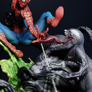May include: A dynamic figurine featuring Spider-Man in a red and blue suit, mid-action, facing off against Venom. Venom is depicted in black and gray with a long tongue and sharp teeth. Green liquid and a web complete the scene.