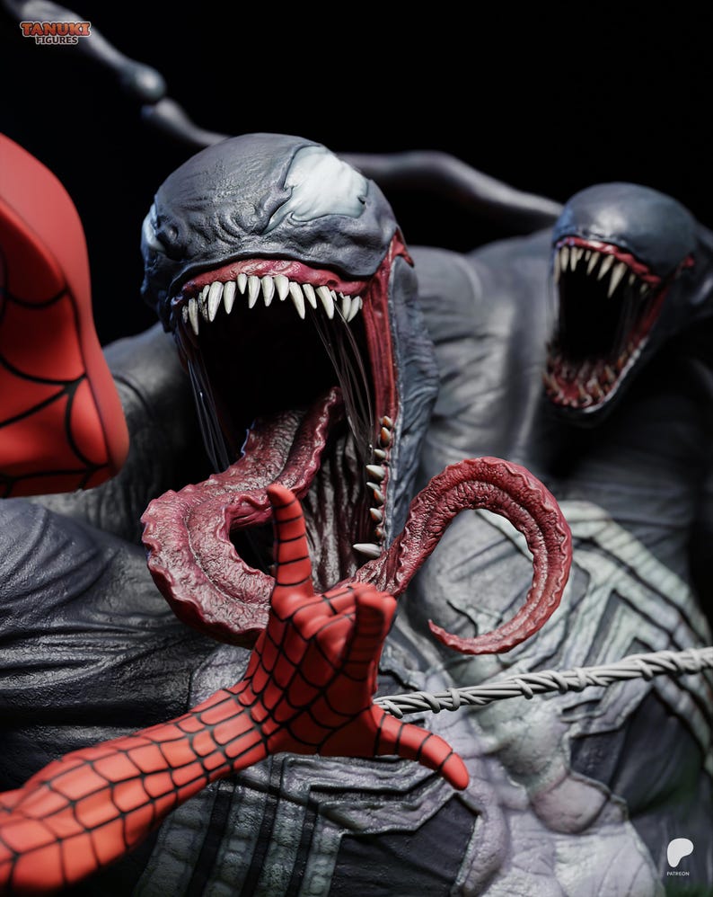May include: A detailed statue of Venom, a Marvel Comics character, with a menacing open mouth and long tongue. The statue features a red hand with a web pattern, and a second Venom head in the background. The statue is dark gray and black.