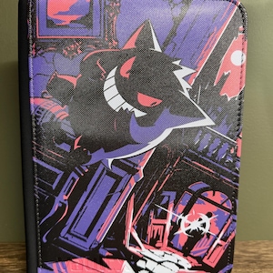 Peut inclure: Un classeur rectangulaire présentant une illustration graphique d'un personnage Gengar violet et noir avec un large sourire. L'arrière-plan représente une scène intérieure sombre et stylisée avec des accents roses et violets.