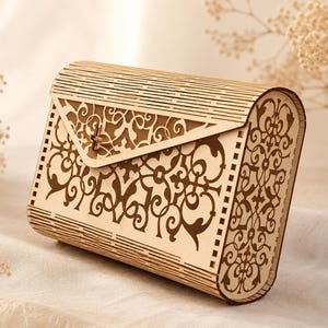 Peut inclure: Une pochette en bois de couleur claire présentant un motif floral complexe découpé au laser sur le rabat avant et les panneaux latéraux. Cet accessoire rectangulaire en forme de boîte possède une base incurvée et un couvercle à charnière.