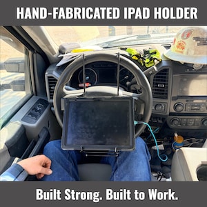 Könnte beinhalten: Handgefertigter iPad-Halter in einem Fahrzeug installiert. Der Halter ist am Lenkrad montiert, mit einem iPad. Der Text "Built Strong. Built to Work." wird darunter angezeigt.