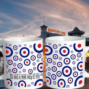 Pode incluir: Duas canecas de cerâmica branca com um padrão de círculos azuis, vermelhos e brancos. Uma das canecas tem o texto "It's just a mod way of life". O fundo mostra o Brighton Pier ao pôr do sol.