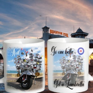 Puede incluir: Dos tazas de cerámica blanca con una imagen colorida de una scooter con muchos espejos y luces. La taza de la izquierda dice "Neil" y la taza de la derecha dice "Go one betta Get a Lambretta".