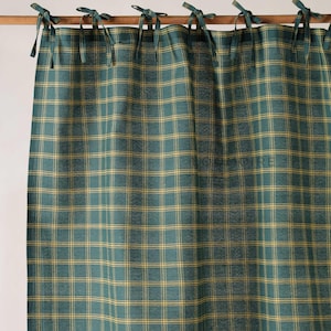 以下が含まれることがあります： 緑と黄色のチェック柄カーテンパネル、結び目ディテール付き。カーテンは、緑と黄色の色合いのクラシックなチェック柄です。上部には、ロッドに掛けるための布製のネクタイが付いています。全体的なテーマは素朴でカントリーです。