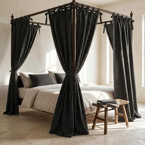Puede incluir: Una cama con dosel de postes de madera oscura, cubierta con cortinas de tela de patrón de cuadrícula en blanco y negro atadas en las esquinas. La cama incluye un edredón blanco, almohadas a juego con el mismo patrón y un taburete de madera.