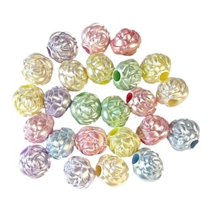 May include: A collection of iridescent, decorative beads in various pastel colors, including pink, yellow, green, and lavender. Each bead has a textured, floral-like design and a hole for stringing. The beads are scattered on a white background.