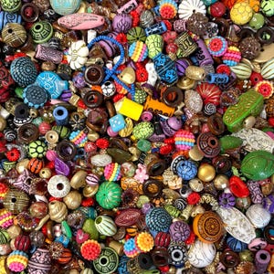 May include: A vibrant assortment of colorful beads in various shapes and sizes. The beads include round, oval, and geometric designs in shades of blue, green, red, yellow, and purple. Some beads have intricate patterns and textures, perfect for jewelry making.