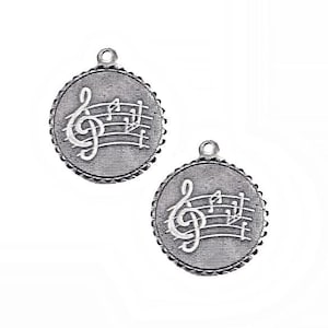 May include: Two silver-toned round charms with a musical note design. Each charm features a treble clef and musical notes within a textured border, perfect for jewelry making or crafting projects. The charms have a small loop at the top for easy attachment.