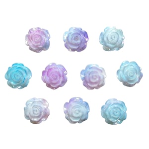 May include: A collection of ten iridescent rose-shaped embellishments in shades of blue, purple, and white. Each rose has detailed petal designs and a glossy finish, perfect for craft projects.