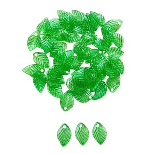 May include: A collection of translucent green leaf-shaped beads. Each bead has a detailed leaf vein pattern and a small hole for stringing. The beads are scattered, with a few arranged at the bottom, all against a white background.