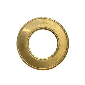 May include: A brass-colored ring with a textured outer edge and a smooth inner surface. The ring is circular with a hole in the center. The metal has a slightly aged appearance.