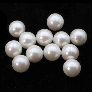 May include: A collection of eleven lustrous, round, white pearls against a black background. The pearls have a smooth, reflective surface, and vary slightly in size. The lighting creates highlights on each pearl.
