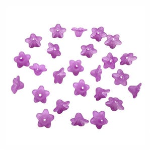 May include: A collection of small, translucent, star-shaped beads in a soft purple hue. Each bead features five petals and a central hole, ideal for jewelry making or craft projects. The beads are scattered against a white background.