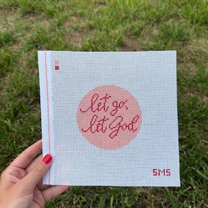 Könnte beinhalten: Ein quadratisches, weißes Stickleinen mit einem pfirsichfarbenen Kreis in der Mitte, der den roten kursiven Text "let go let God" enthält. Eine vertikale rote Linie verläuft am linken Rand und die Buchstaben "SMS" sind unten rechts in Rot aufgedruckt.