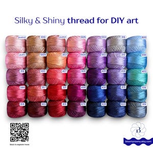 May include: A collection of thirty-five small spools of silky and shiny thread arranged in a grid, featuring a wide spectrum of colors including pinks, reds, purples, and blues. Each spool is labeled with a unique number. Text reads Silky & Shiny thread for DIY art.