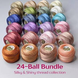 Può includere: Una collezione di 24 gomitoli di filo da ricamo del marchio Kaplan disposti in una griglia. I gomitoli presentano una varietà di colori, tra cui sfumature di blu, rosa, verde, marrone e arancione. Ogni gomitolo ha un'etichetta bianca con il logo Kaplan.