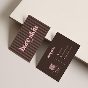 Può includere: Due biglietti da visita marroni. Uno ha strisce marroni e rosa, l'altro è in tinta unita. Entrambi i biglietti presentano il testo "bare skin studio" in rosa. Sono presenti anche informazioni di contatto, un codice QR e icone di social media.