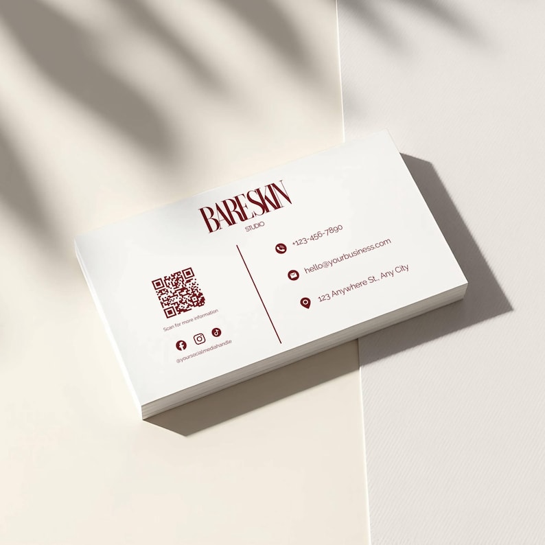 May include: A stack of white business cards with the text "BARESKIN STUDIO" in burgundy. The cards also include a QR code, social media icons, a phone number, an email address, and a physical address.