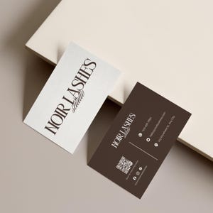 May include: Two business cards with the text "NOIR LASHES Studio". One card is white with black text, the other is brown with white text. The brown card includes contact information and a QR code.