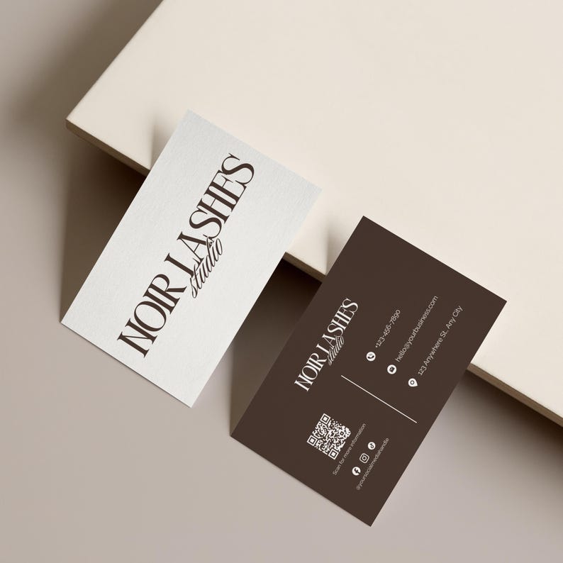 May include: Two business cards with the text "NOIR LASHES Studio". One card is white with black text, the other is brown with white text. The brown card includes contact information and a QR code.