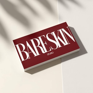 May include: A stack of business cards with the words "BARESKIN STUDIO" in white, bold, sans-serif font on a deep red background. The cards are angled, with a white surface in the background and shadows.