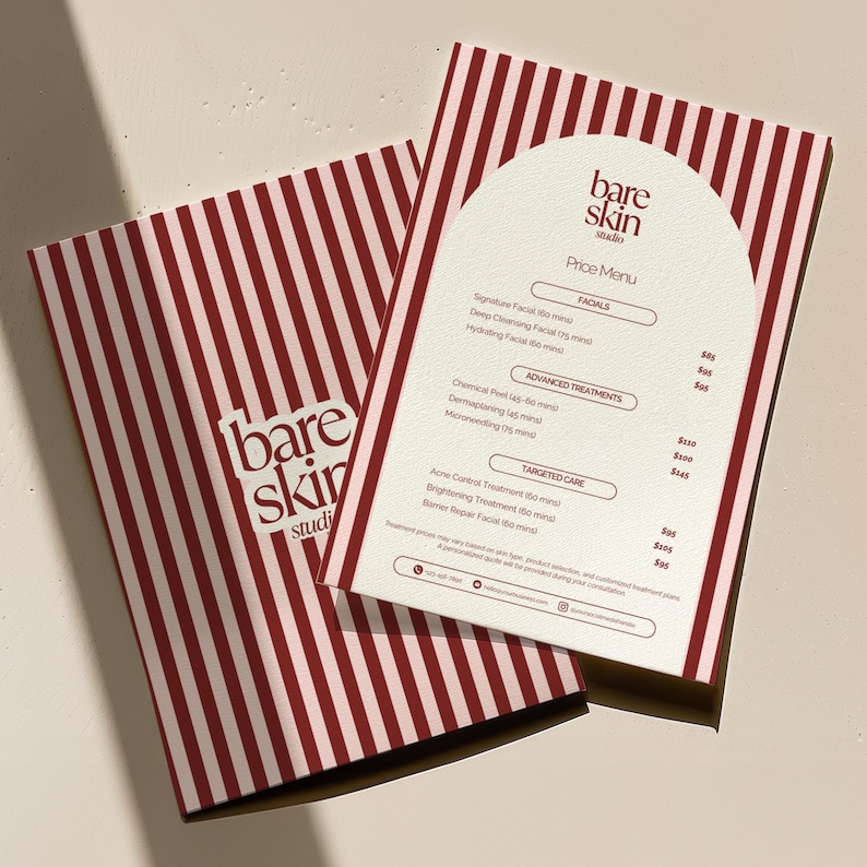 May include: A price menu from Bare Skin Studio, featuring a cream-colored arched top with a list of facials and treatments. The menu is on top of a brochure with a red and white striped pattern. The studio's logo is visible.