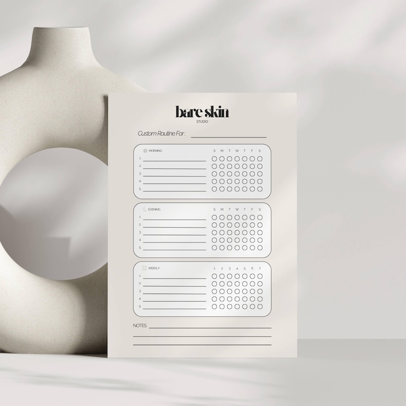 Peut inclure: Un planificateur de routine de soins de la peau beige avec le texte "bare skin studio" en haut. Le planificateur comprend des sections pour les routines du matin, du soir et hebdomadaires, avec des cases &agrave; cocher pour le suivi. Le planificateur est con&ccedil;u pour personnaliser les soins de la peau.