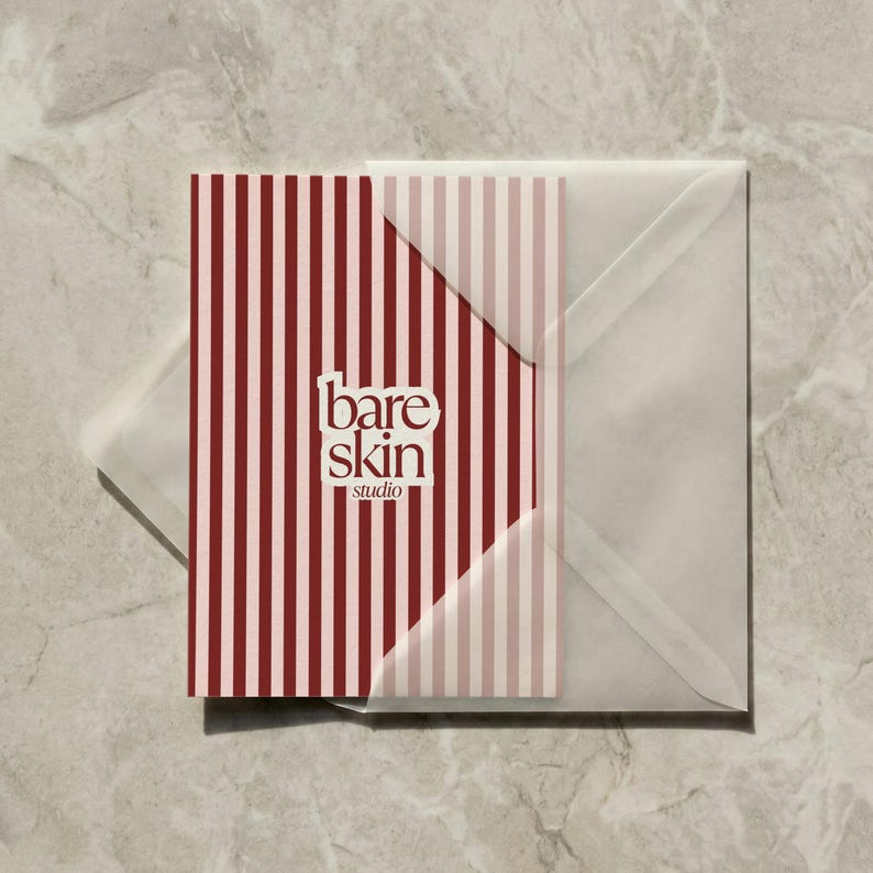 May include: A business card and envelope set. The card features a vertical striped pattern in burgundy and light pink, with the words "bare skin studio" in a white, minimalist font. The envelope is translucent.