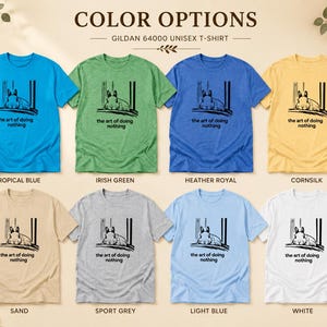Puede incluir: Ocho camisetas unisex Gildan 64000 en azul tropical, verde irland&eacute;s, azul real jaspeado, color ma&iacute;z, arena, gris deportivo, azul claro y blanco. Cada camiseta presenta un gr&aacute;fico negro de un conejo y el texto the art of doing nothing.