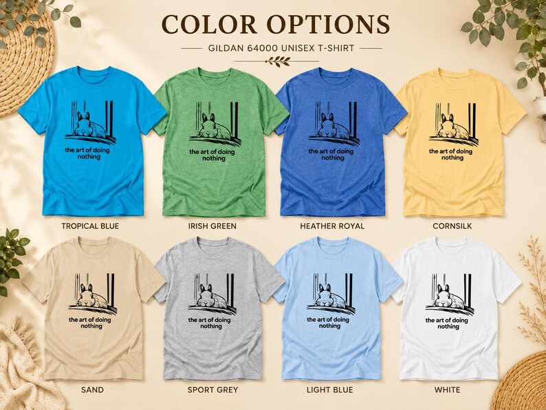 Puede incluir: Ocho camisetas unisex Gildan 64000 en azul tropical, verde irland&eacute;s, azul real jaspeado, color ma&iacute;z, arena, gris deportivo, azul claro y blanco. Cada camiseta presenta un gr&aacute;fico negro de un conejo y el texto the art of doing nothing.
