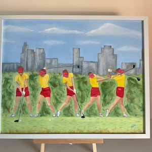 May include: Oil painting of a golf swing sequence. The figures wear yellow shirts, red shorts, and visors. The background features a cityscape under a blue sky with clouds. The painting is framed in a white wooden frame.