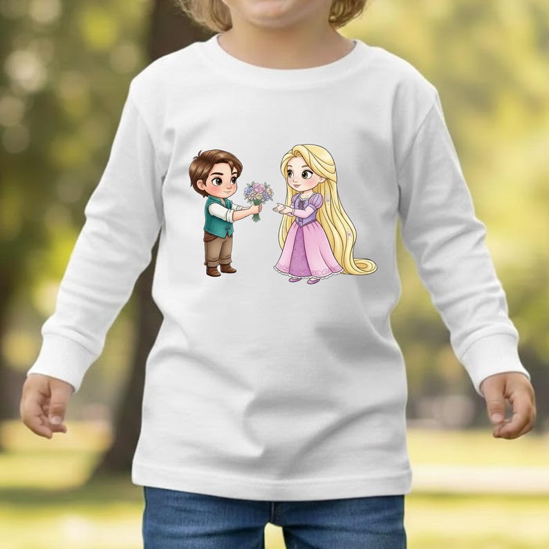 Op de afbeelding: Een wit shirt met lange mouwen voorzien van een grafische illustratie van een jongen met bruin haar in een groen vest die een boeket bloemen aanbiedt aan een blond meisje met lang haar in een paarse jurk op de borst.