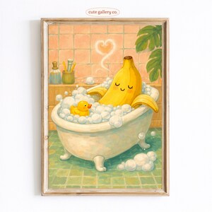 May include: A framed print featuring a cartoon banana relaxing in a bathtub filled with bubbles. A yellow rubber duck floats nearby. The bathroom has a green tiled floor and peach-colored walls. The text "cute gallery co." is in the top left corner.