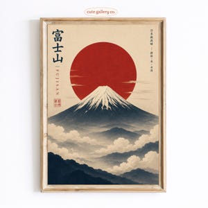 May include: A framed wall art print featuring a stylized illustration of Mount Fuji with a large red sun in the background. The mountain is dark blue with a snow-capped peak, surrounded by clouds. Text includes '富士山', 'FUJISAN', and Japanese characters.