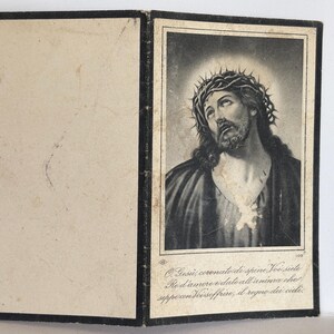 May include: Vintage religious print featuring a black and white portrait of Jesus wearing a crown of thorns. The print is in a black frame and includes Italian text at the bottom. The print is open, revealing a blank page on the left.