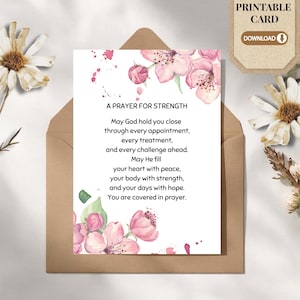 May include: A white rectangular card featuring pink watercolour cherry blossoms at the top and bottom, with the black text A PRAYER FOR STRENGTH followed by a prayer for healing and comfort, placed inside a brown paper envelope.