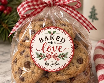 May include: A clear plastic bag filled with chocolate chip cookies, tied with a red and white gingham ribbon. A circular sticker on the front features the text BAKED with love by Julia, decorated with holly leaves, berries, and a small bow.