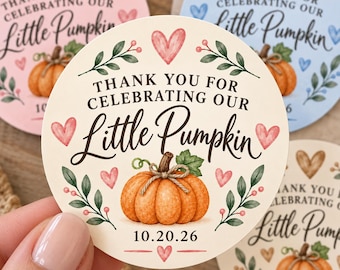 May include: A round cream-colored sticker featuring a central orange pumpkin illustration with green leaves and twine. The text reads "THANK YOU FOR CELEBRATING OUR Little Pumpkin" with the date "10.20.26" below, surrounded by small pink hearts and green foliage.