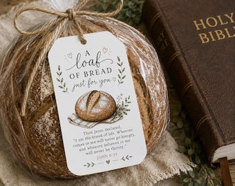 Puede incluir: Una hogaza de pan redonda en una bolsa de celofán transparente, atada con hilo de bramante, y una etiqueta de regalo que dice "Una hogaza de pan solo para ti". Una Biblia encuadernada en cuero marrón es visible en el fondo. La etiqueta incluye un versículo bíblico y un dibujo de una hogaza de pan.